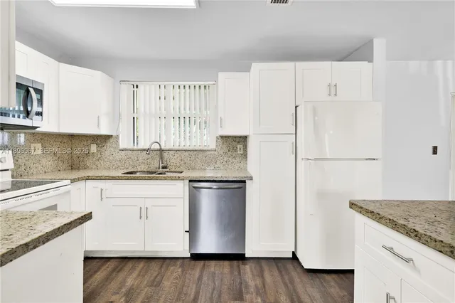 a kitchen with granite countertop white cabinets and white appliances