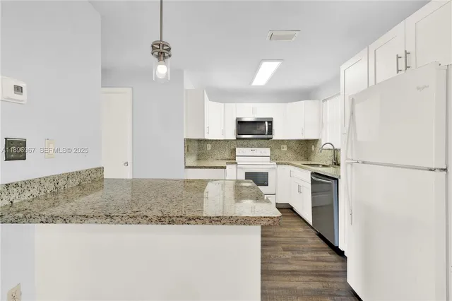 a kitchen with kitchen island granite countertop wooden cabinets a sink dishwasher a refrigerator and a stove