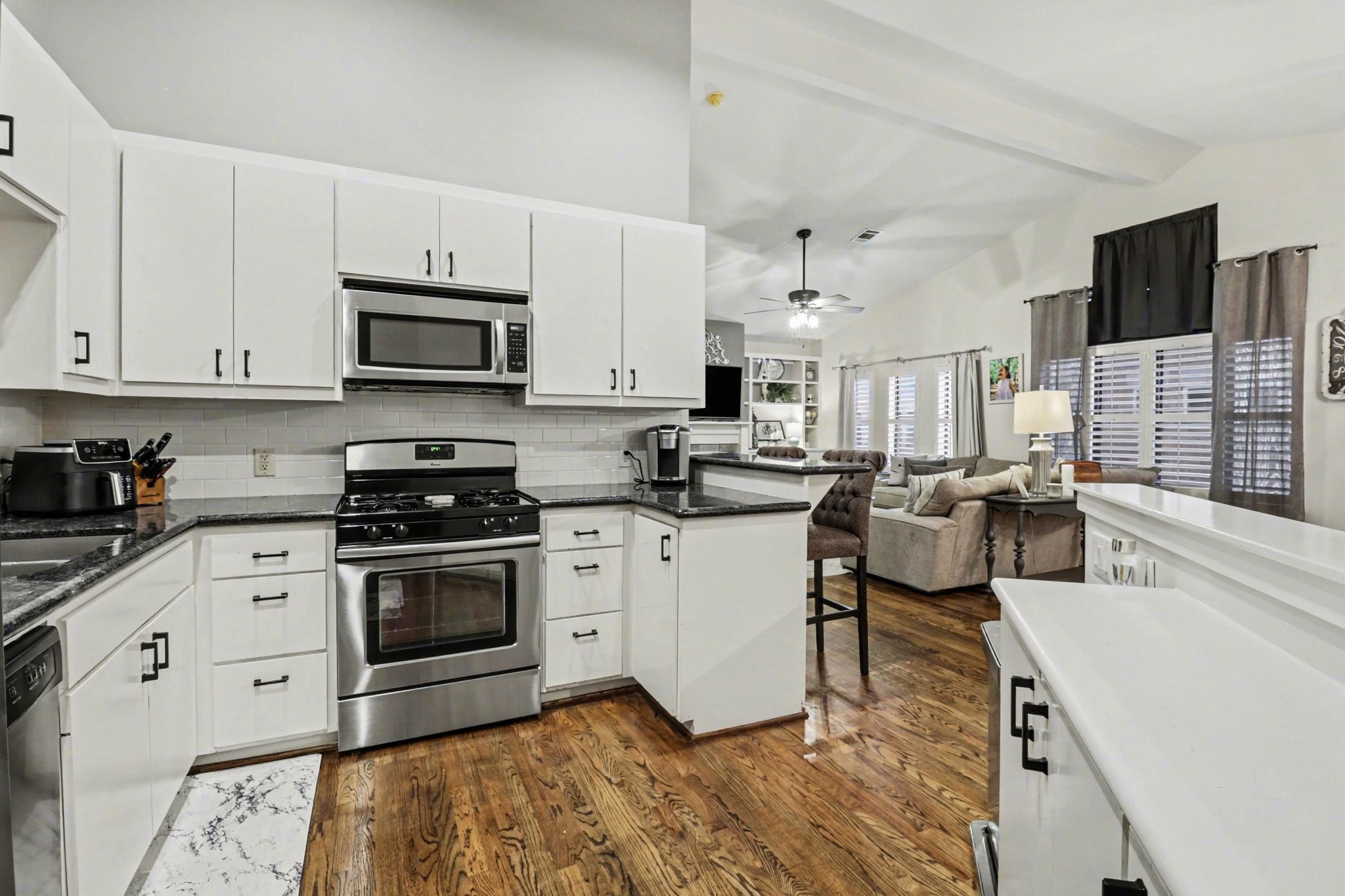 914 West 25th Street, Unit 2 Houston, TX 77008 - Photo 11 of 30 a kitchen with stainless steel appliances white cabinets a sink a stove a microwave and wooden floors