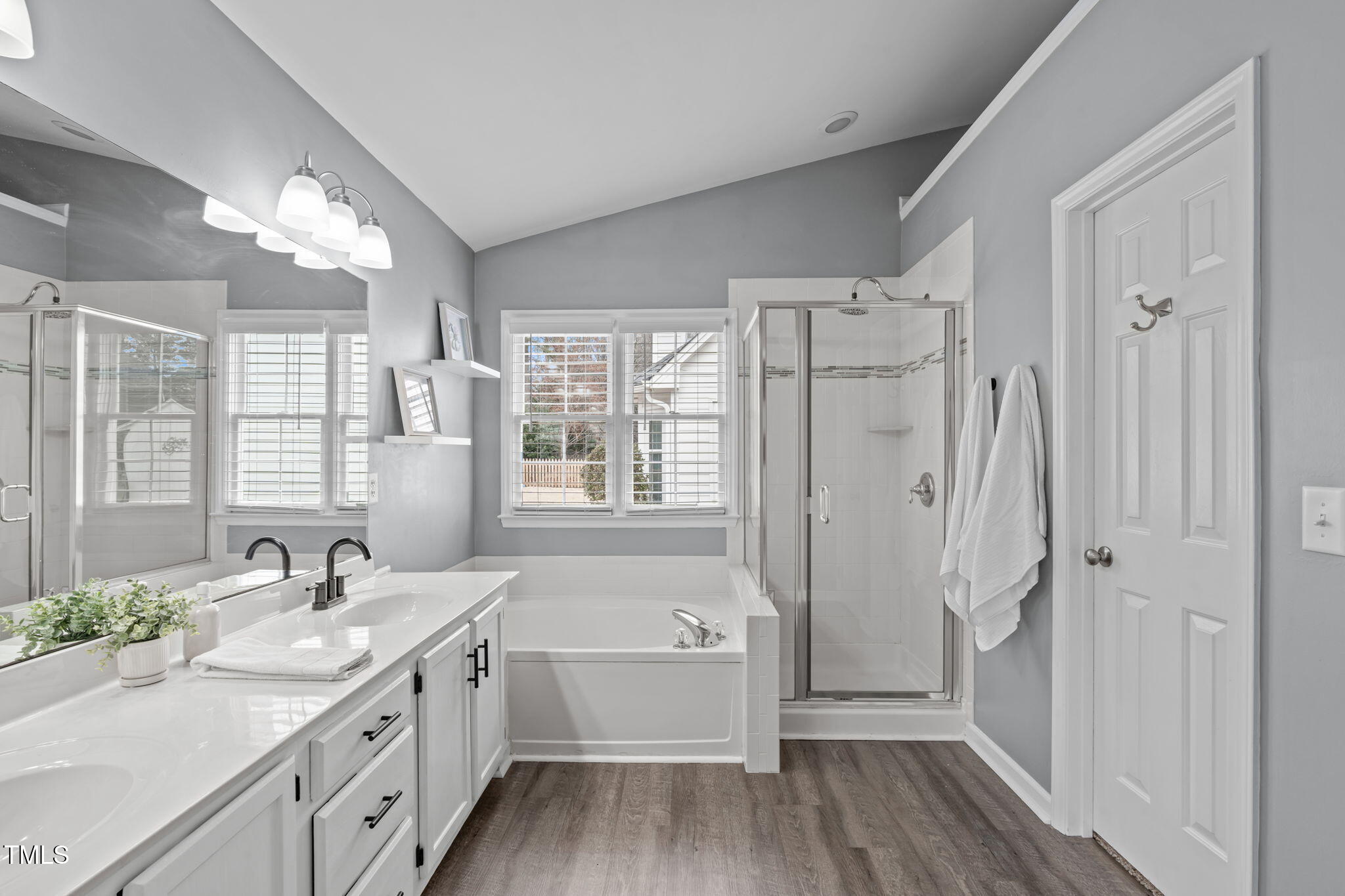 11228 North Radner Way Raleigh, NC 27613 - Photo 20 of 34 a bathroom with a double vanity sink a large mirror a shower and a bathtub