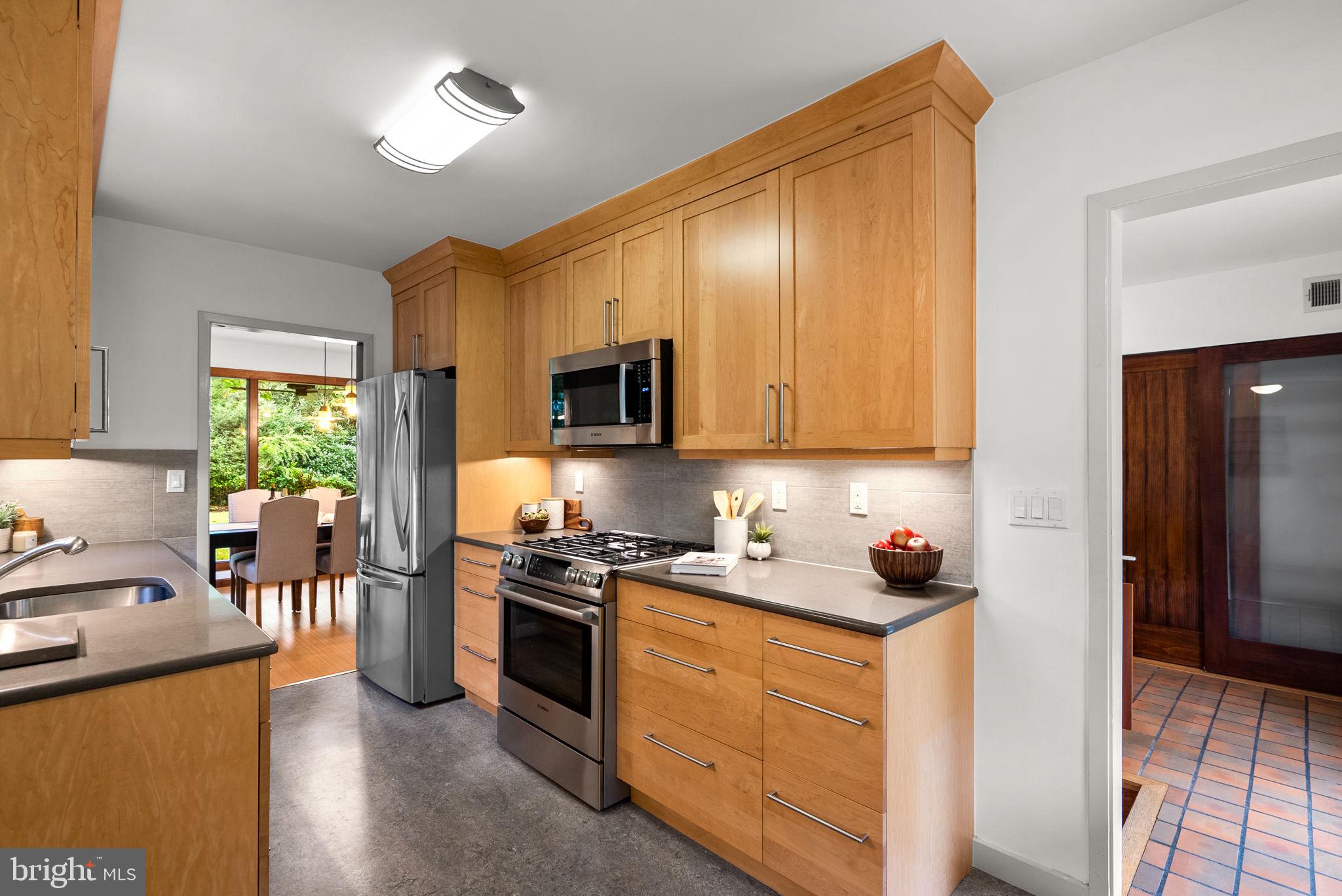 9109 Fairview Road Silver Spring, MD 20910 - Photo 17 of 46 a kitchen with stainless steel appliances granite countertop a stove top oven a sink dishwasher a dining table and chairs with wooden floor