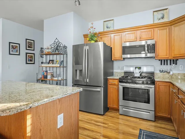 a kitchen with stainless steel appliances granite countertop a refrigerator a stove and a sink with wooden floor