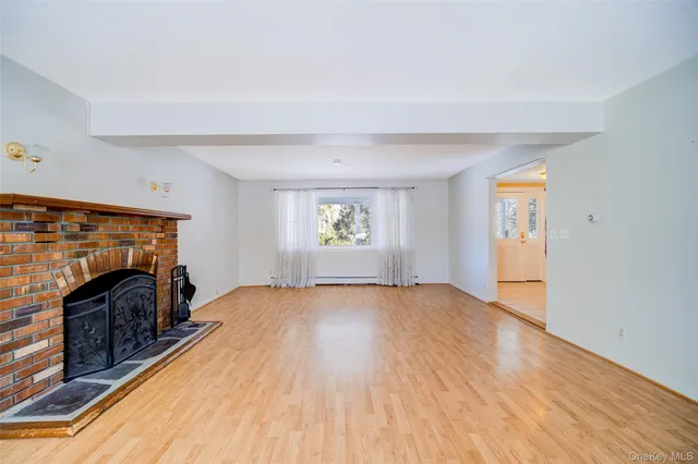 an empty room with windows fireplace and wooden floor