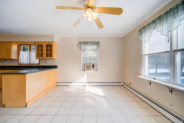 a view of an empty room with window and chandelier fan