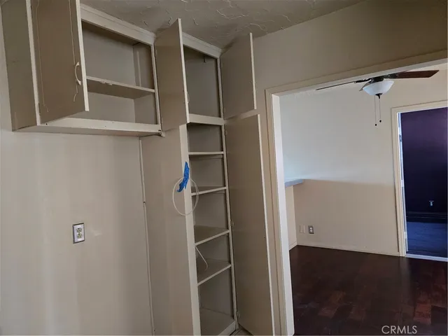 an empty room with wooden floor closet and windows