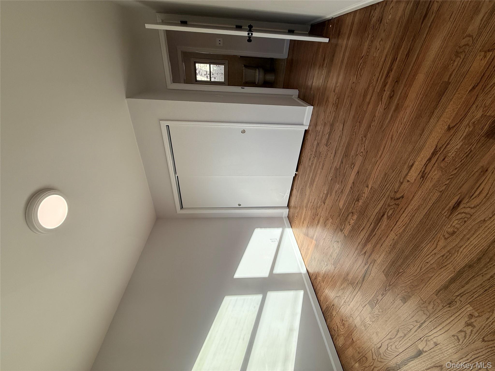 130-09 58th Road Queens, NY 11355 - Photo 11 of 18 Unfurnished bedroom featuring wood finished floors and a closet