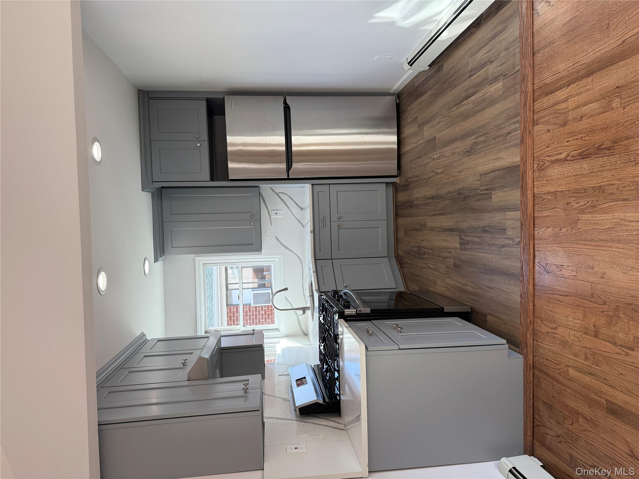 130-09 58th Road Queens, NY 11355 - Photo 2 of 18 Kitchen featuring stainless steel range oven, refrigerator, gray cabinets, baseboard heating, and dark wood-style floors