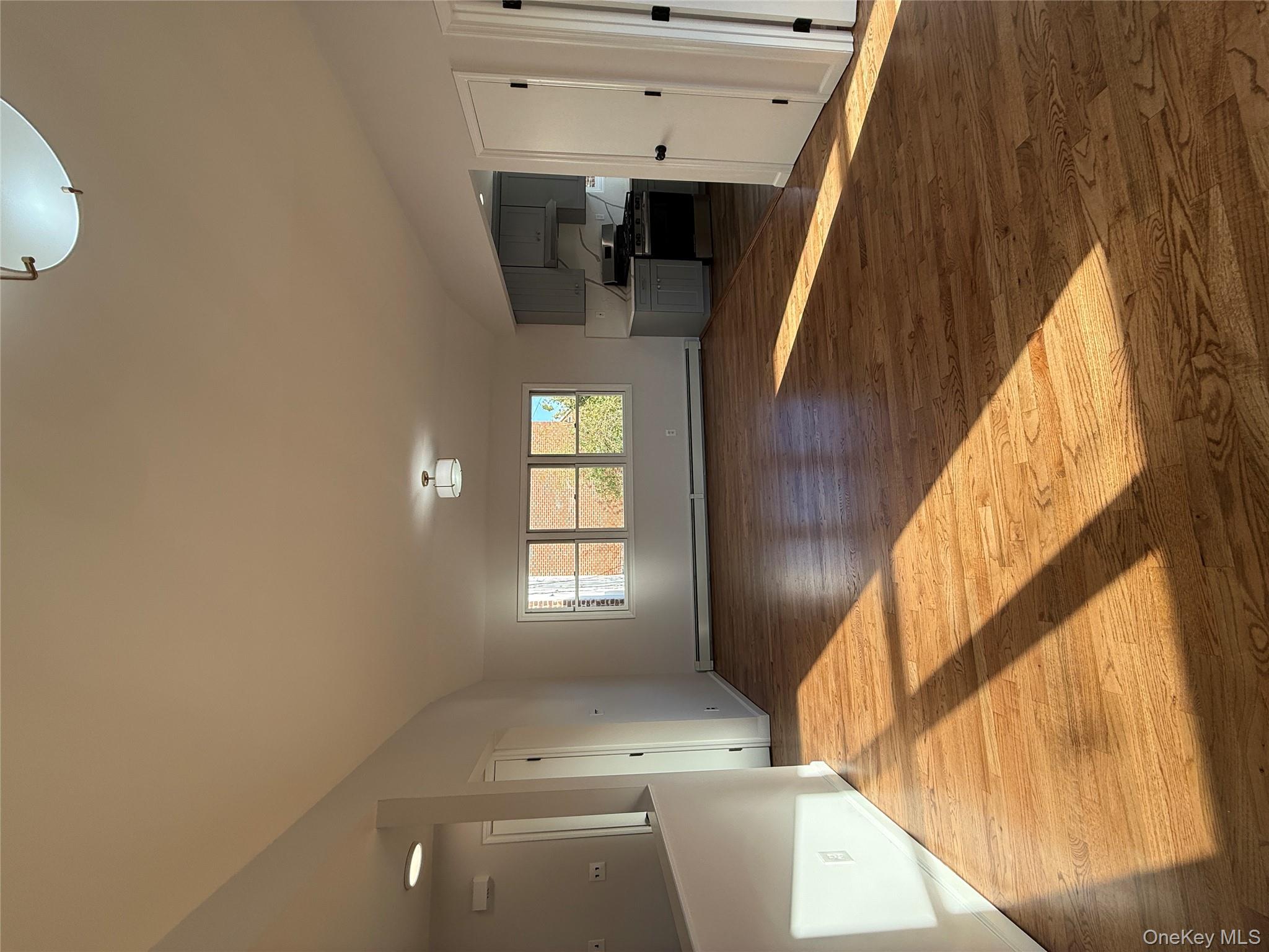 130-09 58th Road Queens, NY 11355 - Photo 5 of 18 Unfurnished living room featuring dark wood-style flooring and a baseboard radiator