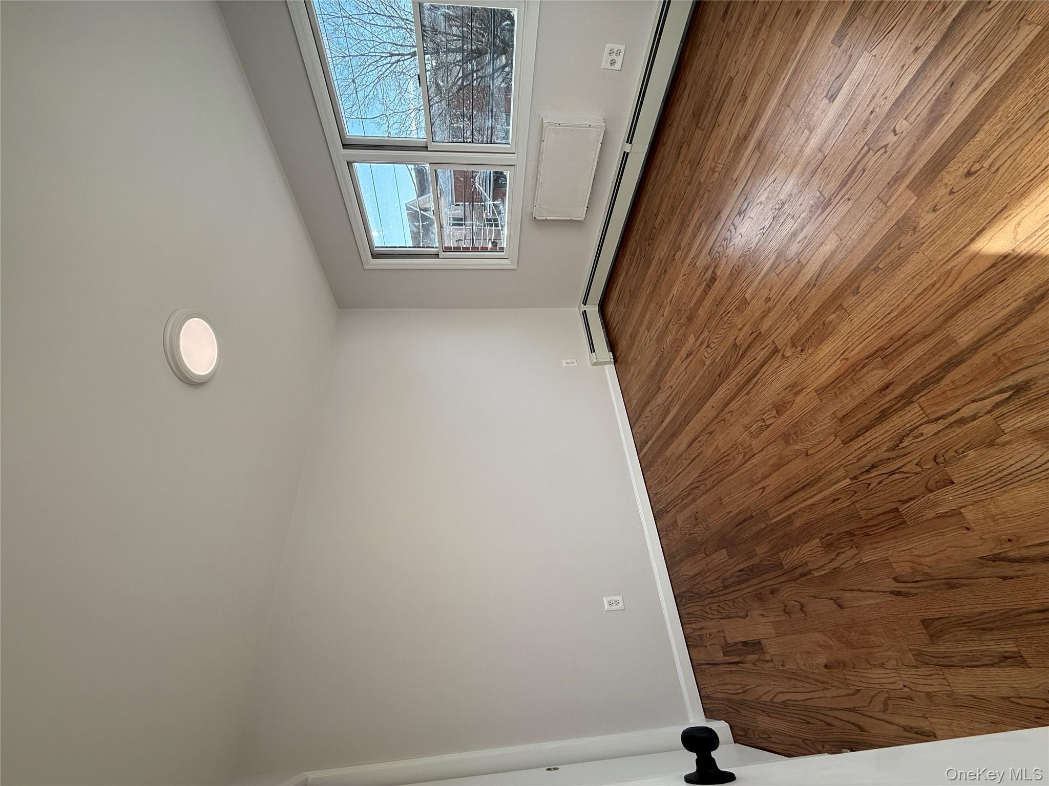 130-09 58th Road Queens, NY 11355 - Photo 6 of 18 Empty room featuring wood finished floors and baseboards