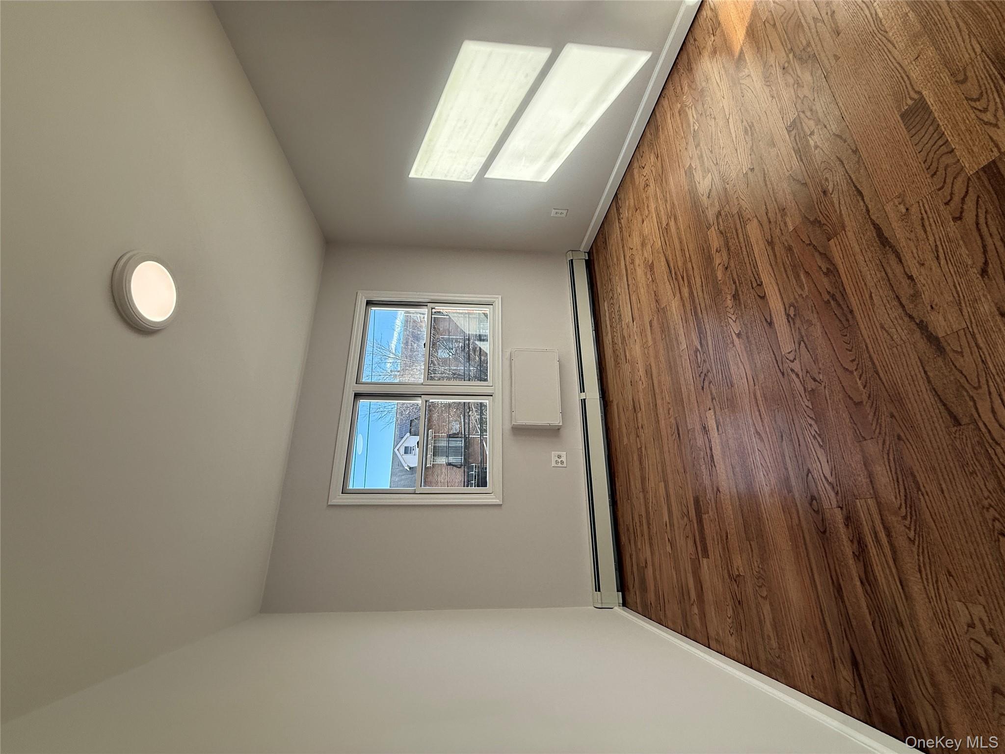 130-09 58th Road Queens, NY 11355 - Photo 10 of 18 Unfurnished room with a baseboard heating unit and hardwood / wood-style flooring