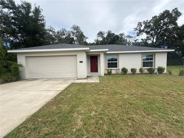 front view of house with yard and trees in the background