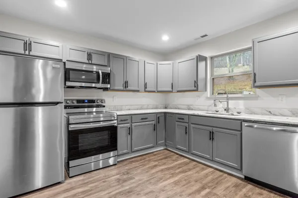 a kitchen with stainless steel appliances granite countertop a stove a sink and a refrigerator