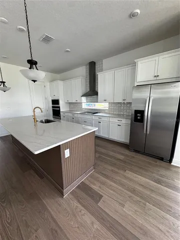 a kitchen with stainless steel appliances a sink a stove a refrigerator and cabinets