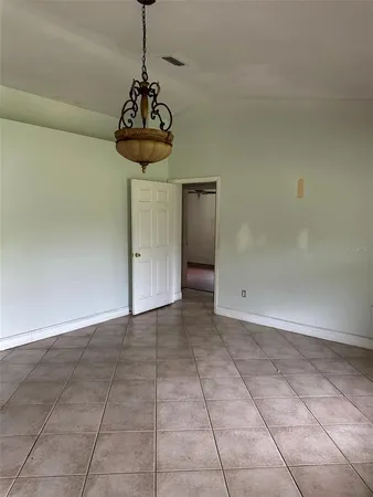 a view of a room with a chandelier fan and kitchen view