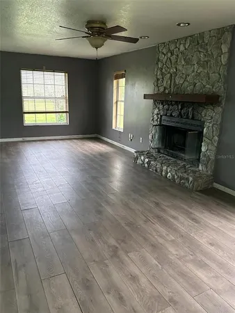 an empty room with windows and fireplace
