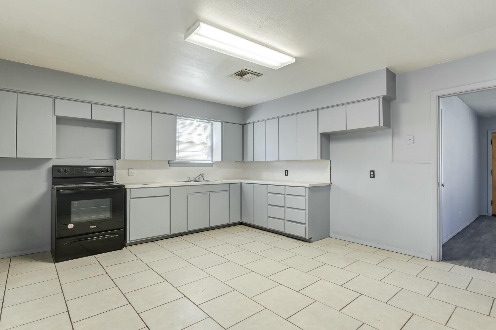 3013 45th Street Lubbock, TX 79413 - Photo 12 of 30 a kitchen with a stove top oven and cabinets