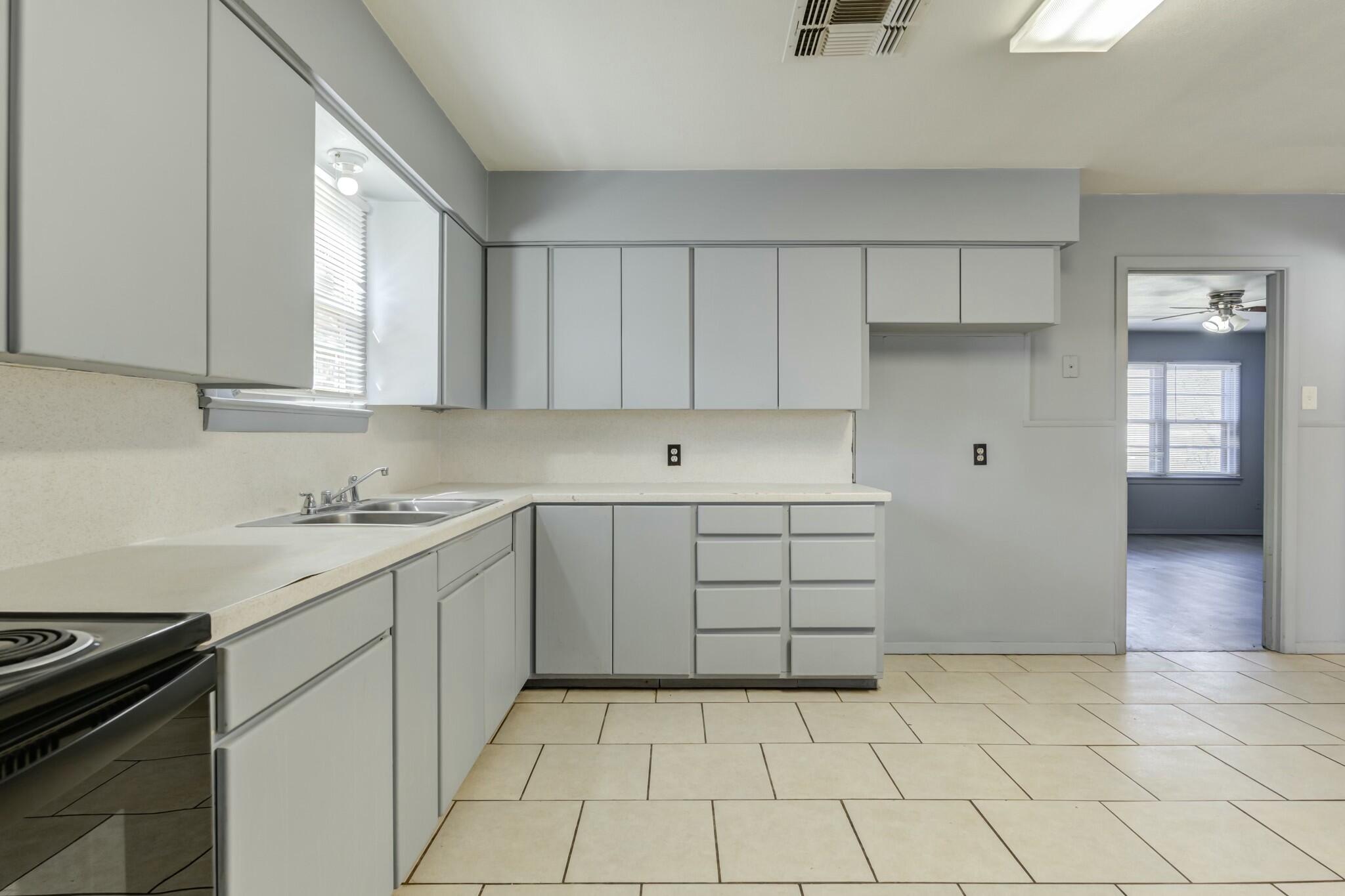 3013 45th Street Lubbock, TX 79413 - Photo 14 of 30 a kitchen with a stove sink and cabinets