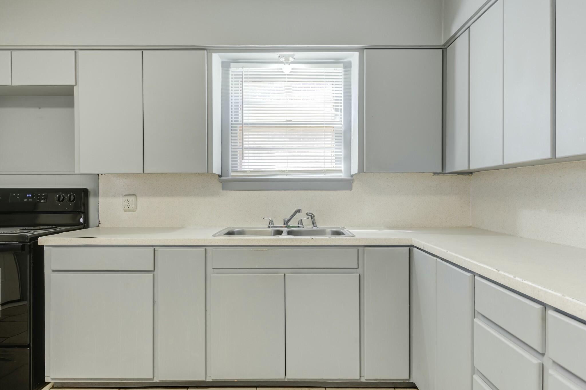 3013 45th Street Lubbock, TX 79413 - Photo 15 of 30 a kitchen with white cabinets appliances a sink and a window