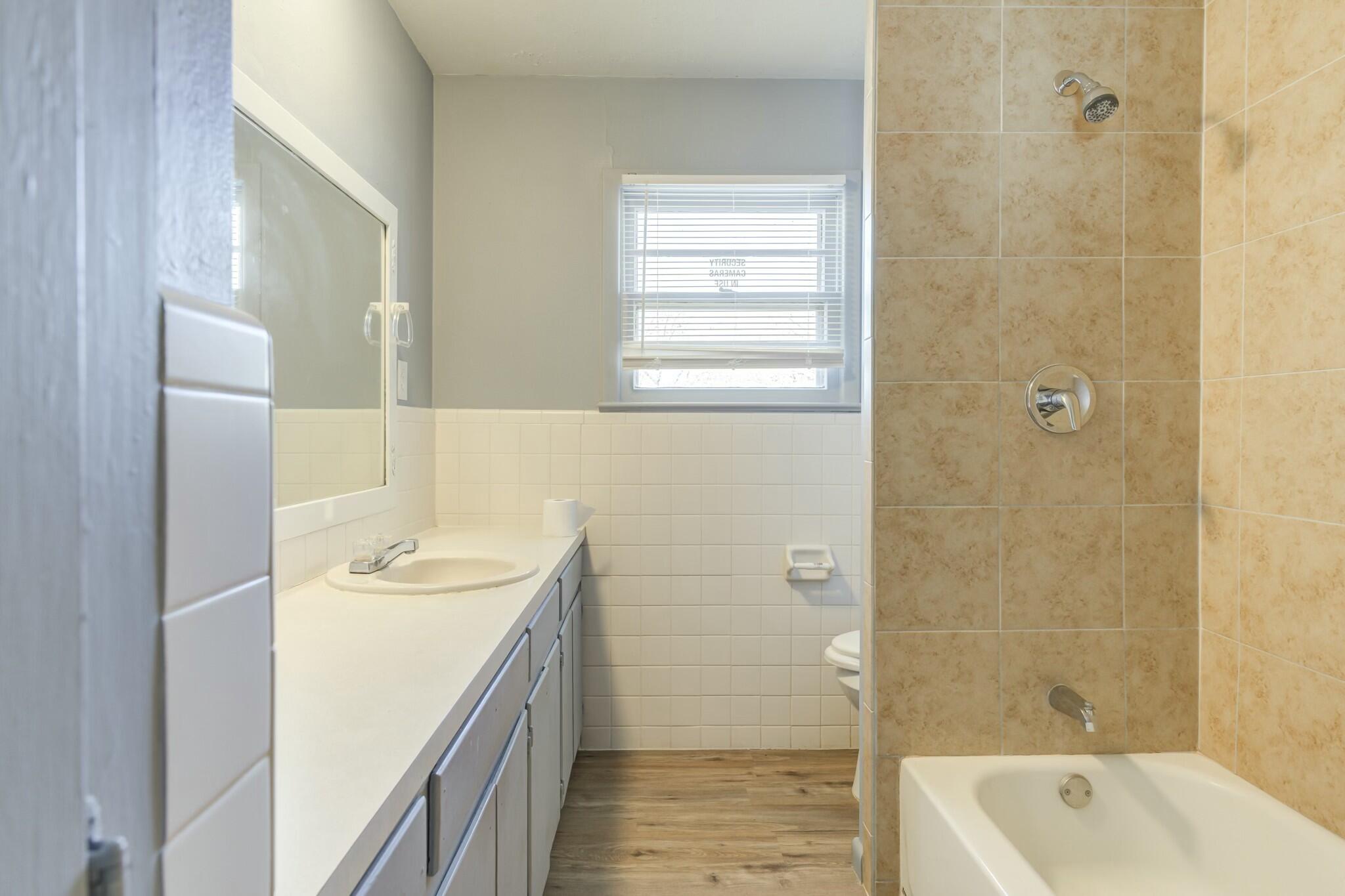 3013 45th Street Lubbock, TX 79413 - Photo 21 of 30 a bathroom with a tub sink and mirror