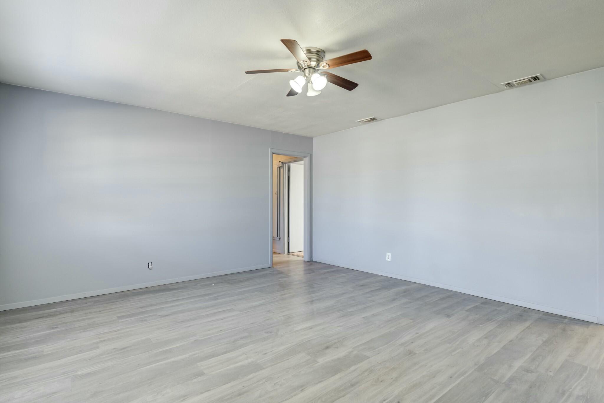 3013 45th Street Lubbock, TX 79413 - Photo 4 of 30 an empty room with wooden floor and ceiling fan