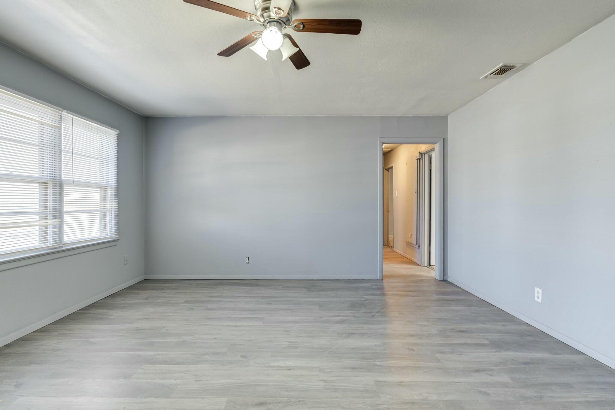 3013 45th Street Lubbock, TX 79413 - Photo 5 of 30 an empty room with wooden floor fan and windows
