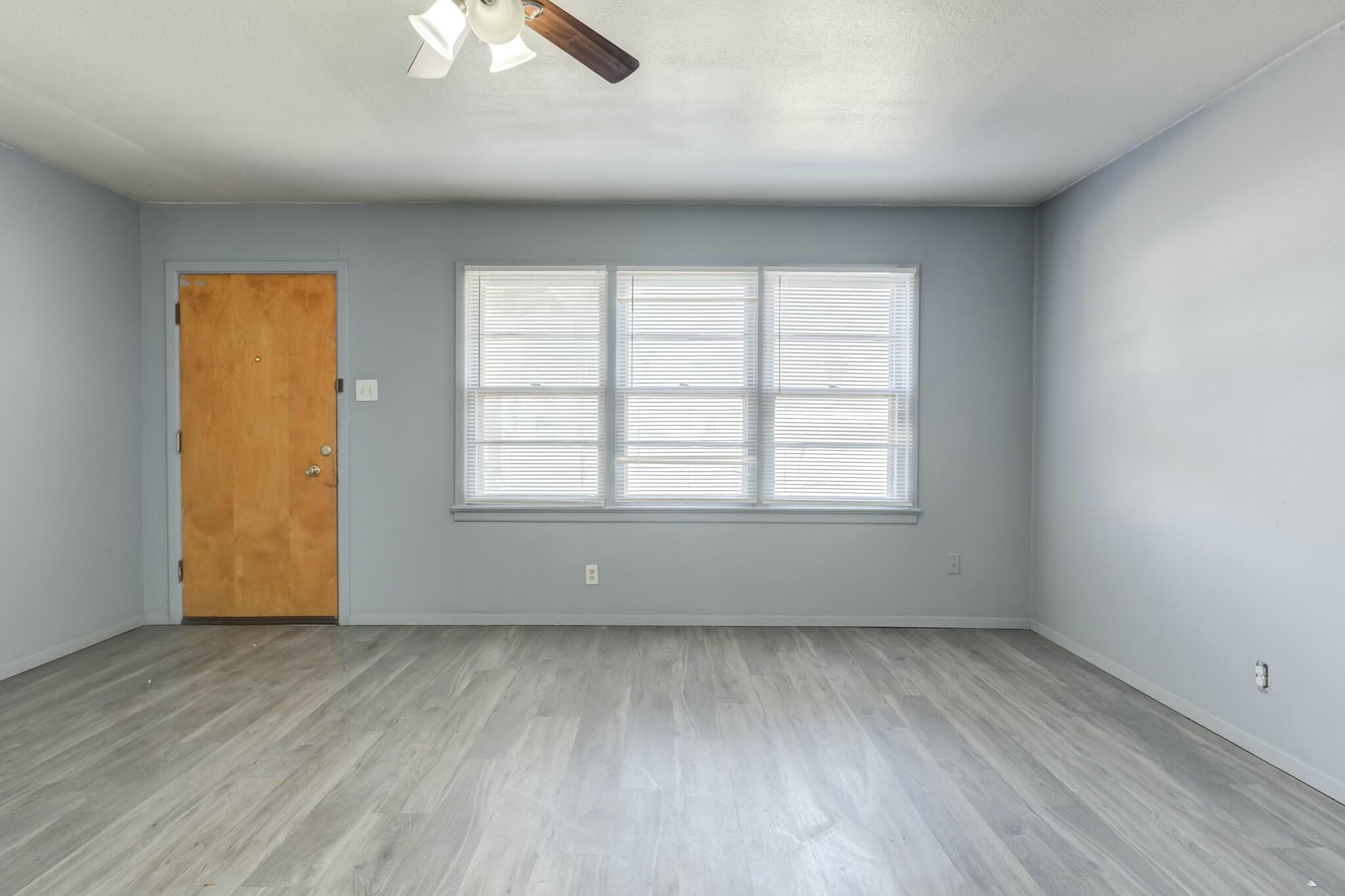 3013 45th Street Lubbock, TX 79413 - Photo 7 of 30 an empty room with wooden floor and windows