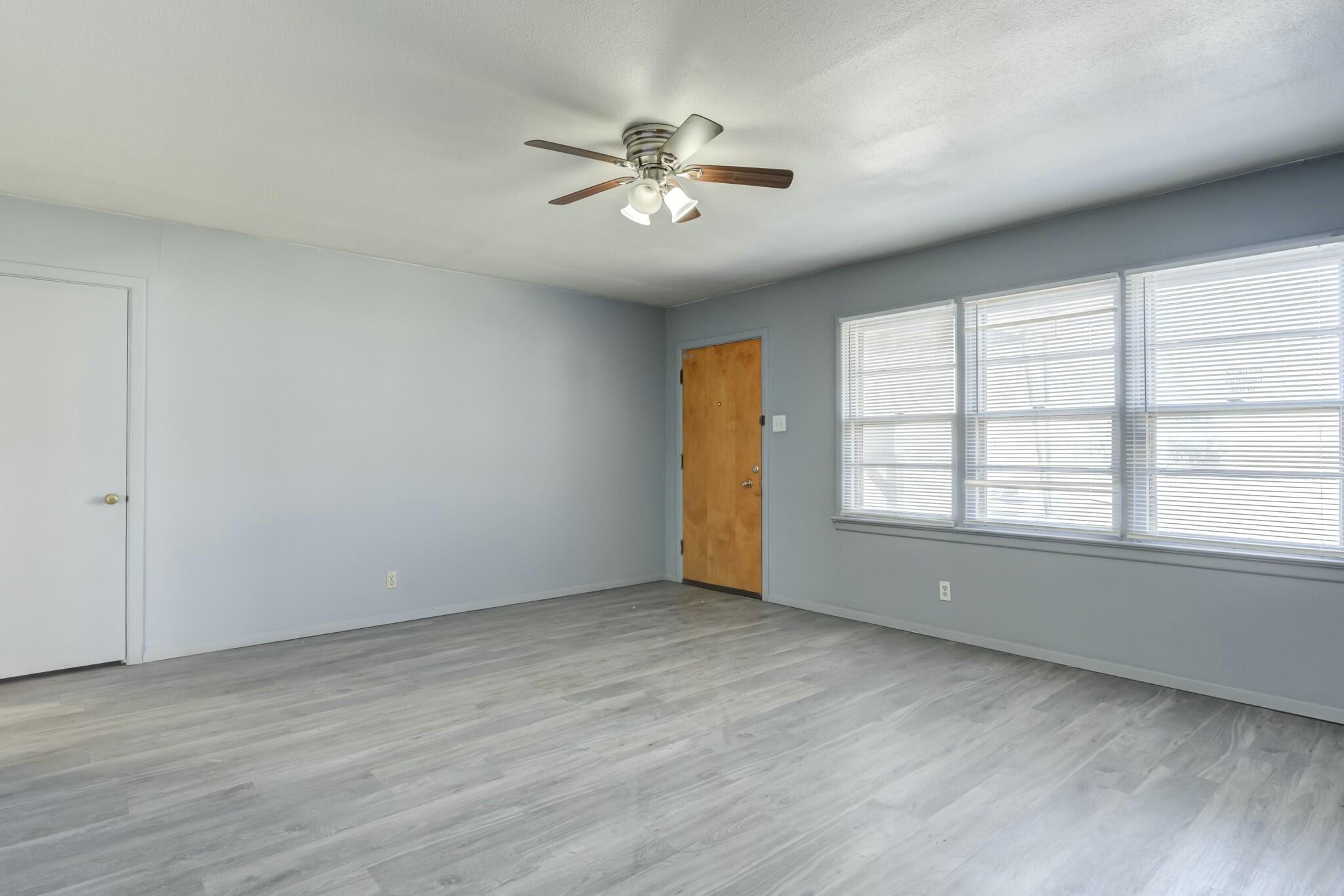 3013 45th Street Lubbock, TX 79413 - Photo 8 of 30 an empty room with wooden floor fan and windows