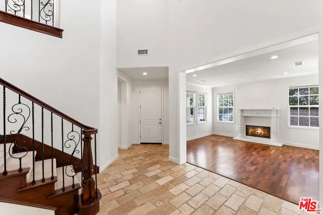 a view of empty room with wooden floor and kitchen