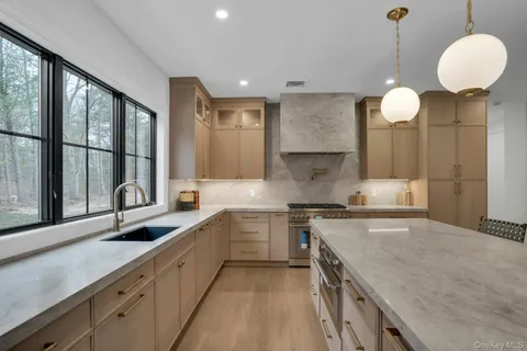 a kitchen with stainless steel appliances granite countertop a stove and a view of living room