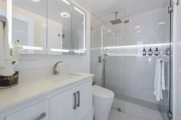 a bathroom with a sink a toilet a mirror and shower