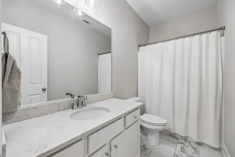 a bathroom with a granite countertop sink toilet and a mirror