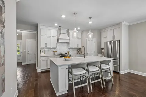 a kitchen with stainless steel appliances a dining table chairs stove refrigerator and cabinets