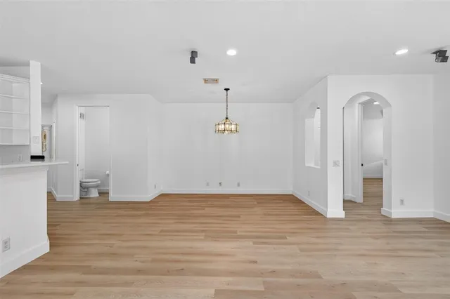 a view of an empty room with window and wooden floor