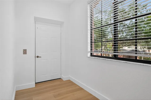 an empty room with wooden floor and a hallway