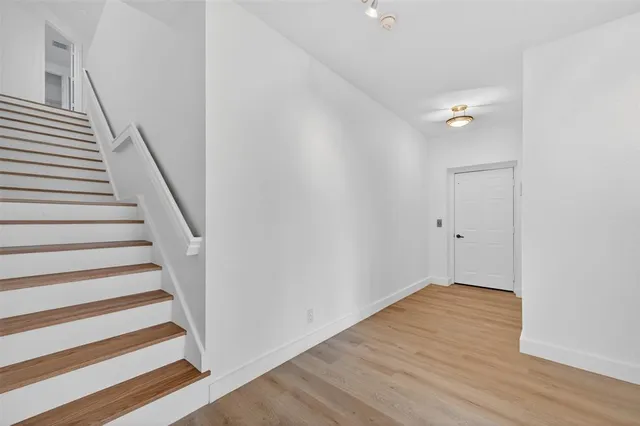 a view of a hallway with wooden floor and a bathroom