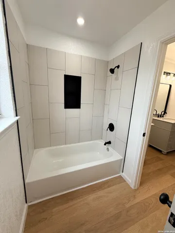 a bathroom with a tub a window and a flat screen tv