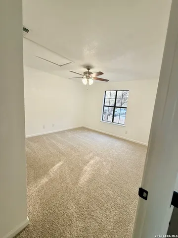 an empty room with windows and ceiling fan