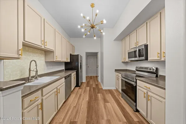 a kitchen with granite countertop a stove top oven a sink dishwasher and a microwave oven with white cabinets