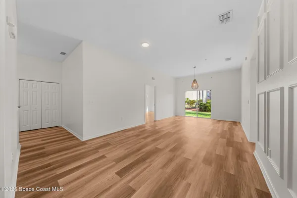 a view of an empty room with wooden floor and a window