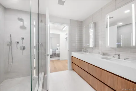 a bathroom with a double vanity sink mirror and shower