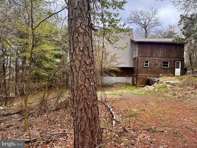 a backyard of a house with large trees and wooden fence