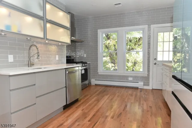 a kitchen with stainless steel appliances cabinets and a large window