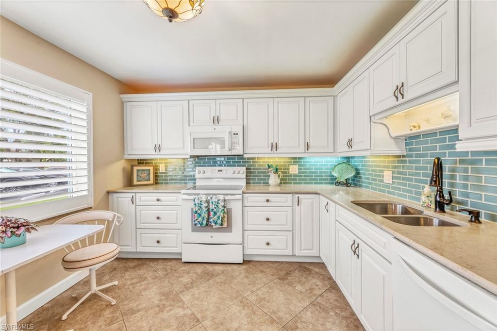 a kitchen with granite countertop a white stove top oven sink and cabinets