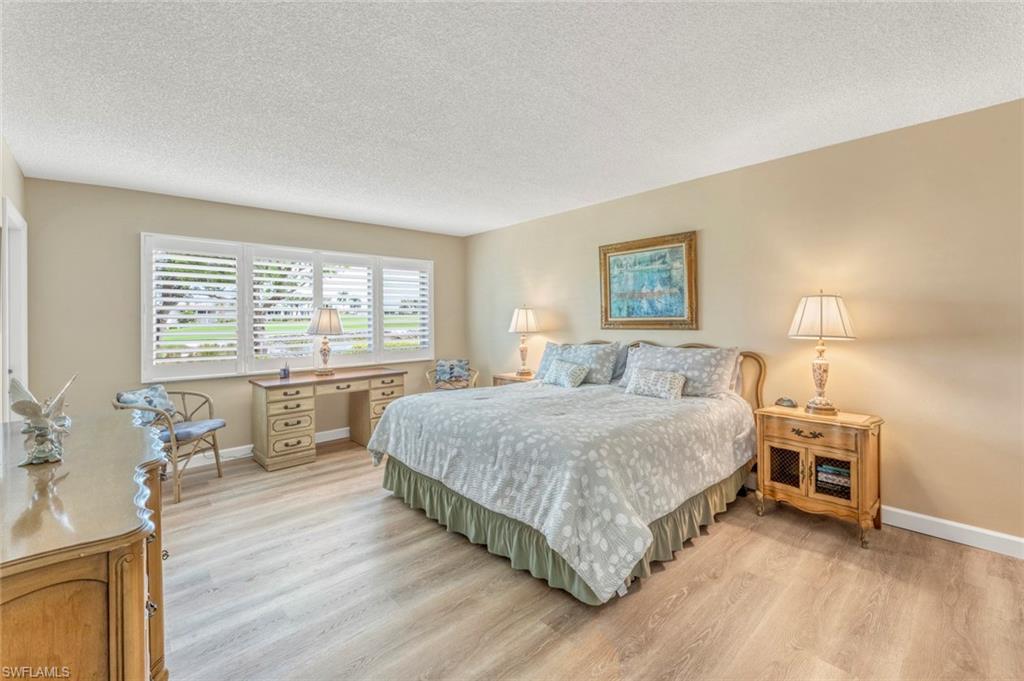 245 Quails Nest Road, Unit 3 Naples, FL 34112 - Photo 20 of 50 a spacious bedroom with a bed a table and three large window with wooden floor