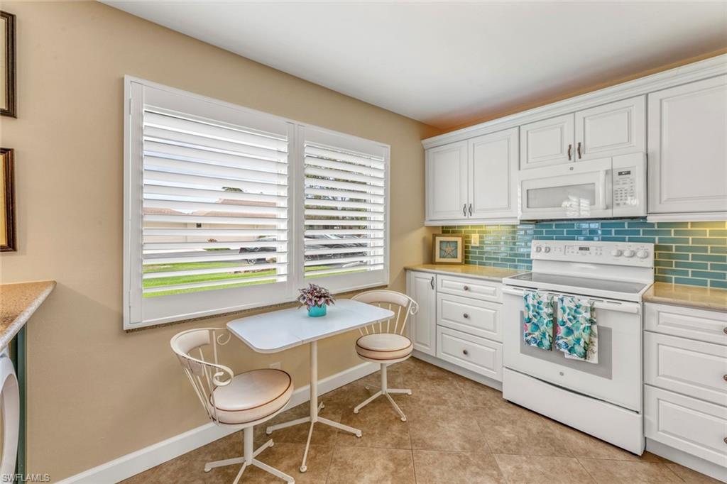 245 Quails Nest Road, Unit 3 Naples, FL 34112 - Photo 10 of 50 a kitchen with a stove a table and chairs in it