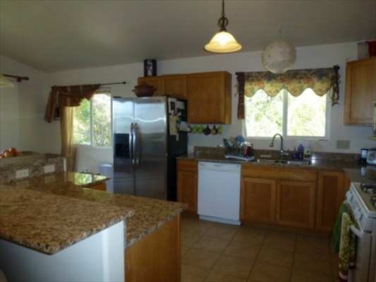 82-1225 Kinue Road Captain Cook, HI 96704 - Photo 8 of 25 a kitchen with stainless steel appliances granite countertop a sink a stove a refrigerator a washer dryer and a dining table