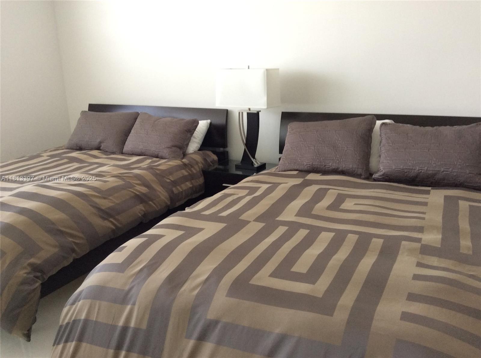 100 Lincoln Road, Unit 1214 Miami Beach, FL 33139 - Photo 17 of 17 a bedroom with two beds and a lamp on the dresser