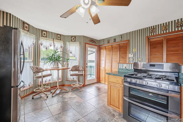 a kitchen with stainless steel appliances granite countertop a refrigerator a sink dishwasher a stove with wooden cabinets and floor