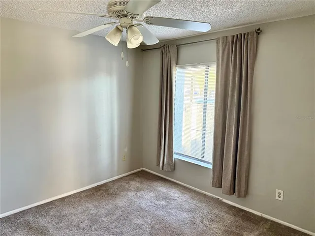 an empty room with windows and fan
