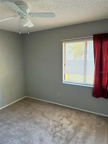 an empty room with windows and fan